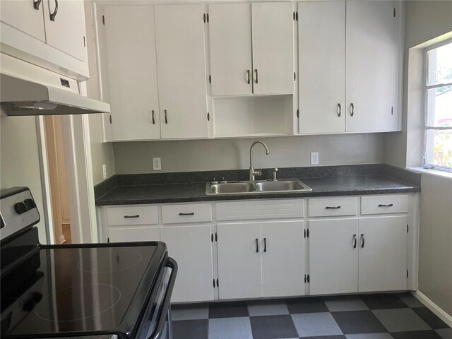 kitchen with sink, range with electric stovetop, dark tile patterned floors, and white cabinets