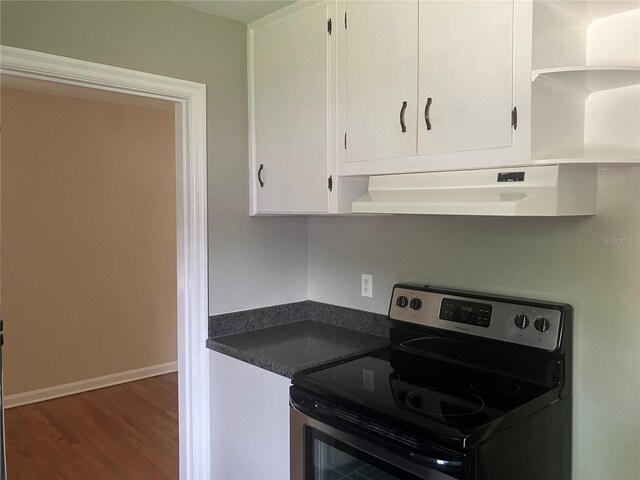 kitchen featuring white cabinets, electric range, dark hardwood / wood-style flooring, and wall chimney range hood