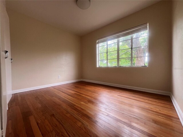 spare room featuring hardwood / wood-style flooring and vaulted ceiling