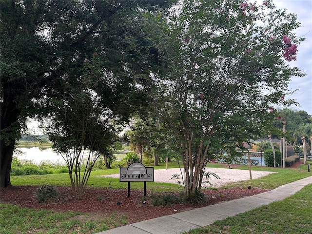 view of property's community with a water view, a lawn, and volleyball court