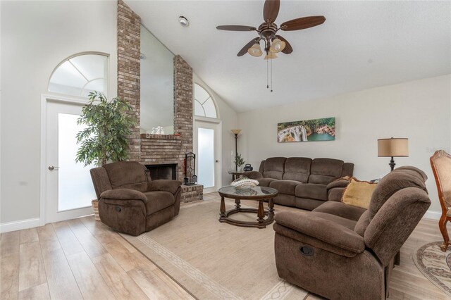 living room featuring high vaulted ceiling, ceiling fan, a brick fireplace, and light hardwood / wood-style floors