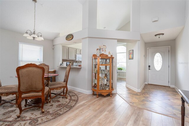 entrance foyer with high vaulted ceiling, light hardwood / wood-style floors, and a chandelier