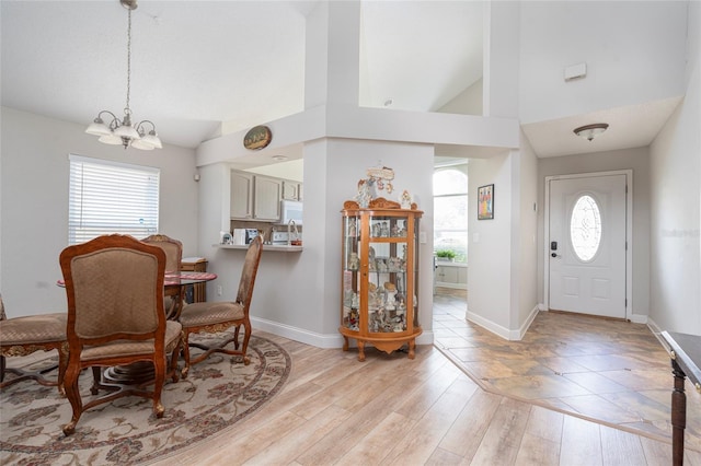 entryway with a notable chandelier, plenty of natural light, baseboards, and light wood-style floors