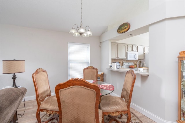 dining space with an inviting chandelier, light wood-style flooring, baseboards, and vaulted ceiling