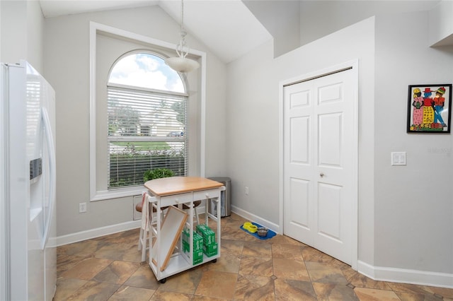 office featuring lofted ceiling, stone finish floor, and baseboards