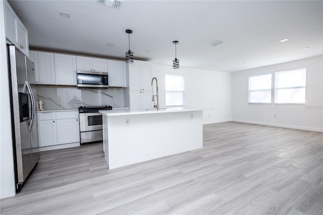 kitchen featuring a kitchen island with sink, decorative backsplash, plenty of natural light, and stainless steel appliances