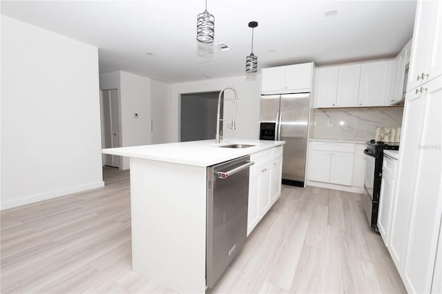 kitchen with light wood-type flooring, white cabinets, backsplash, stainless steel appliances, and a center island with sink