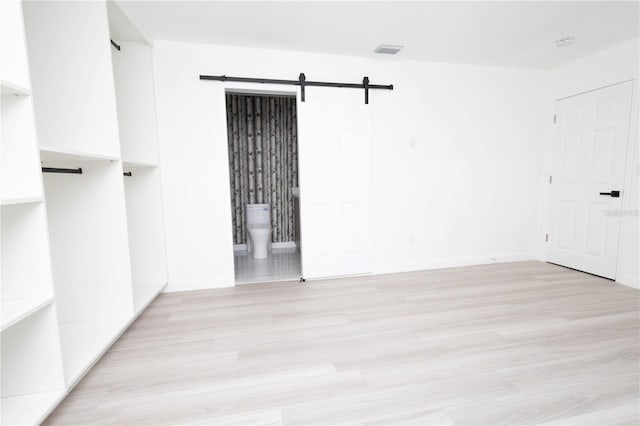 spare room featuring light hardwood / wood-style flooring and a barn door