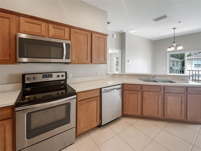 kitchen featuring a notable chandelier, stainless steel appliances, pendant lighting, sink, and light tile patterned floors