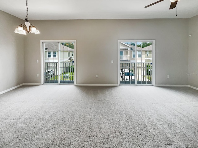 carpeted empty room featuring a healthy amount of sunlight and ceiling fan with notable chandelier