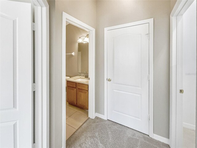 hall with sink and light colored carpet