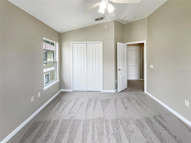 unfurnished bedroom with vaulted ceiling, light colored carpet, a closet, and ceiling fan