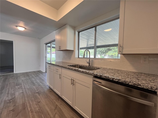 kitchen with stainless steel dishwasher, white cabinetry, hardwood / wood-style floors, sink, and stone countertops