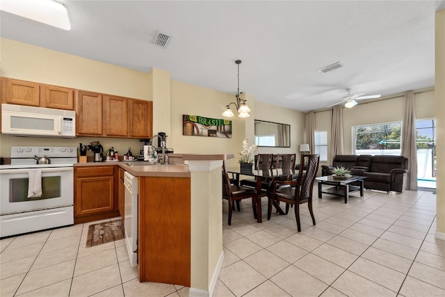 kitchen with white appliances, sink, hanging light fixtures, light tile patterned floors, and ceiling fan with notable chandelier