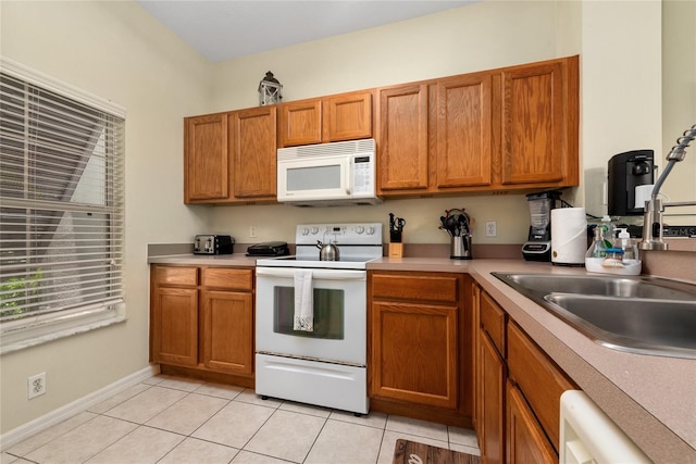 kitchen featuring sink, light tile patterned floors, and white appliances