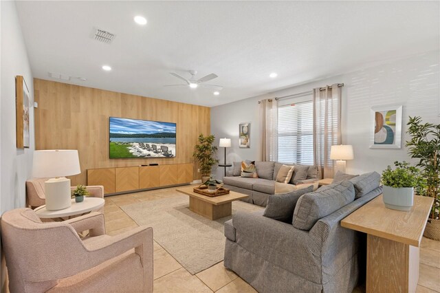 living room featuring wooden walls, light tile patterned floors, and ceiling fan