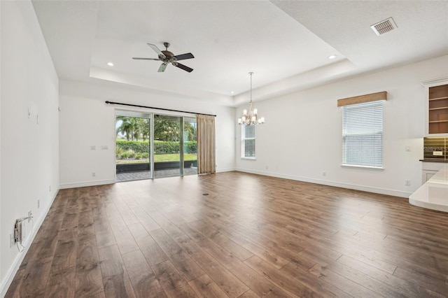 unfurnished living room featuring hardwood / wood-style floors, a tray ceiling, and ceiling fan with notable chandelier