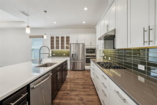 kitchen featuring appliances with stainless steel finishes, sink, decorative light fixtures, backsplash, and dark hardwood / wood-style flooring