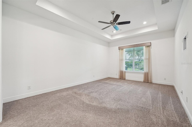 carpeted empty room featuring a tray ceiling and ceiling fan