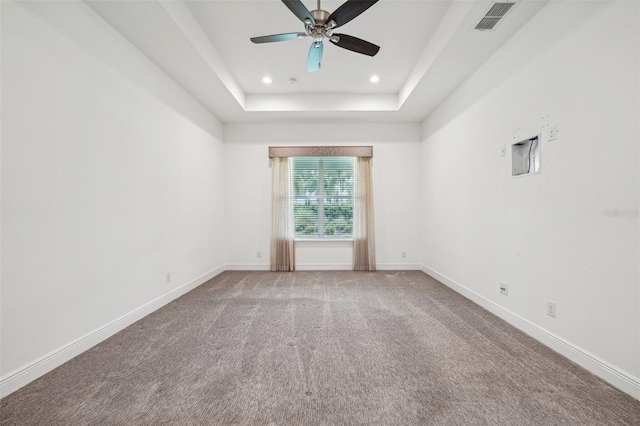 carpeted spare room with ceiling fan and a raised ceiling