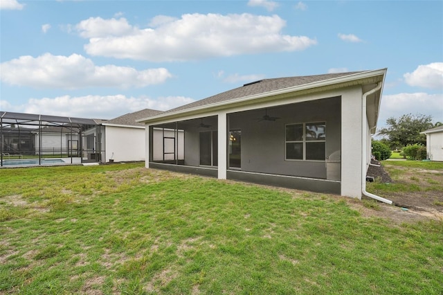 rear view of property with glass enclosure, ceiling fan, and a lawn