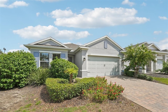 ranch-style house with decorative driveway, an attached garage, and stucco siding