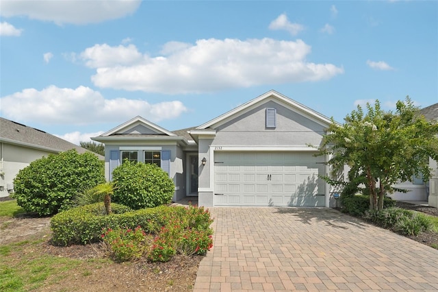 ranch-style home featuring decorative driveway, a garage, and stucco siding