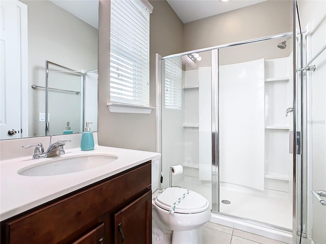 bathroom featuring a shower with shower door, vanity, tile patterned floors, and toilet