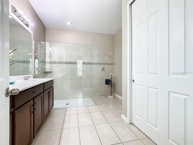 bathroom with tile patterned floors, vanity, and a tile shower