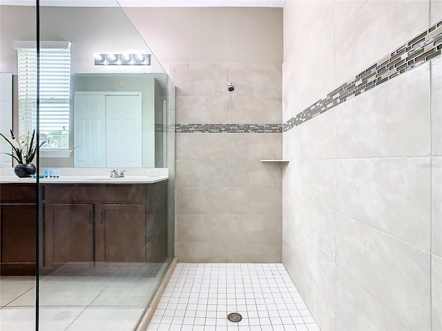 bathroom with a shower with shower door, vanity, tile patterned flooring, and tile walls