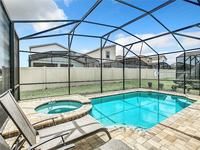 view of pool featuring an in ground hot tub, glass enclosure, and a patio