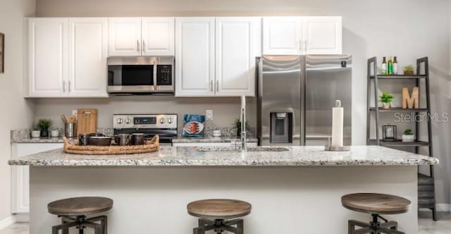 kitchen with white cabinetry, light stone countertops, and stainless steel appliances