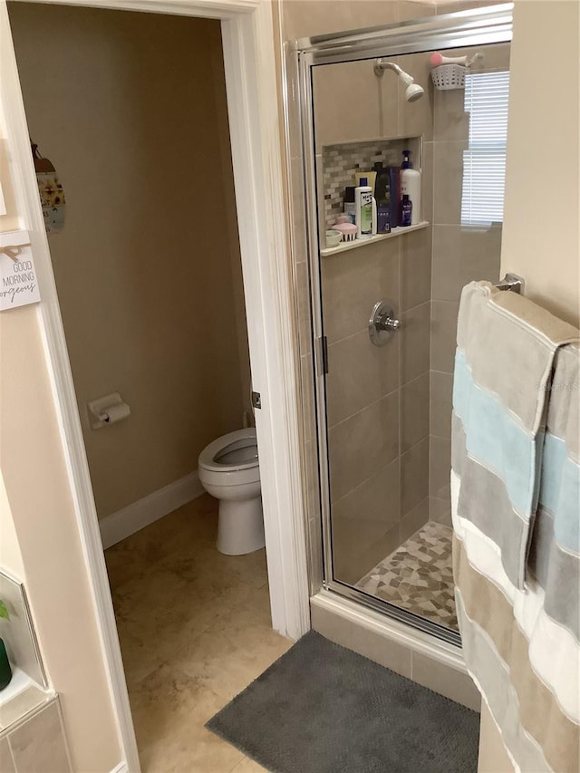 bathroom featuring a shower with door and toilet