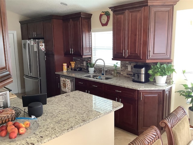 kitchen featuring stainless steel appliances, light stone countertops, sink, and decorative backsplash