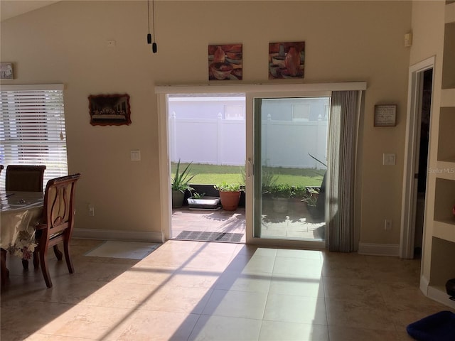 doorway to outside featuring light tile patterned floors, vaulted ceiling, and a wealth of natural light