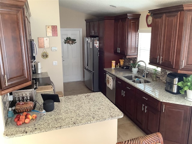 kitchen with sink, appliances with stainless steel finishes, tasteful backsplash, light stone countertops, and vaulted ceiling