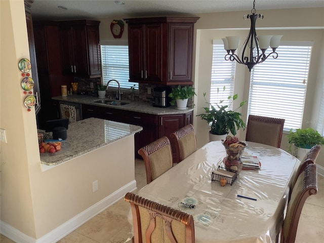 dining area featuring a healthy amount of sunlight, sink, light tile patterned floors, and an inviting chandelier