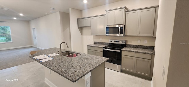 kitchen featuring a kitchen island with sink, stainless steel appliances, a sink, and gray cabinetry