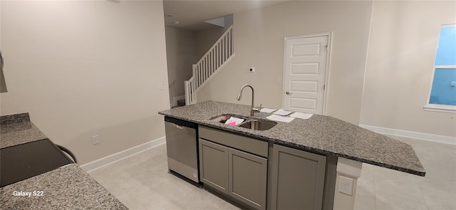 kitchen with dark stone counters, gray cabinetry, dishwasher, light tile patterned floors, and sink