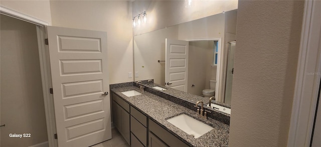 full bathroom with a textured wall, a sink, toilet, and double vanity