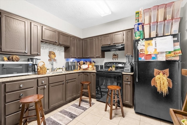 kitchen featuring dark brown cabinets, black appliances, a textured ceiling, and light tile patterned floors