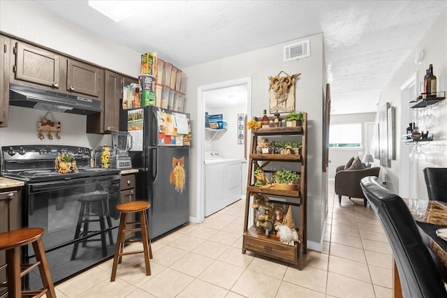 kitchen with separate washer and dryer, black appliances, light tile patterned floors, and a textured ceiling