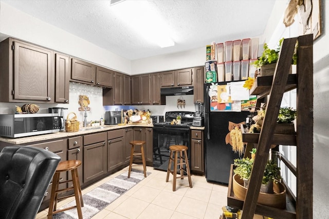 kitchen featuring dark brown cabinets, black appliances, and light tile patterned floors