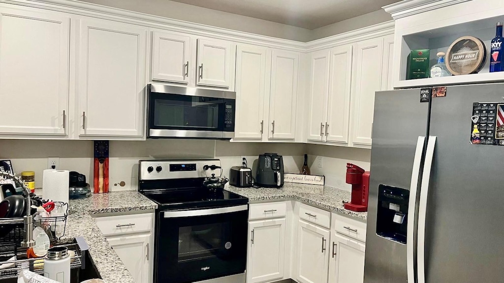 kitchen with white cabinetry, light stone countertops, and appliances with stainless steel finishes