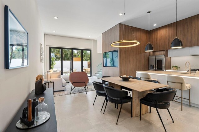 dining room featuring light tile patterned floors, sink, and wooden walls