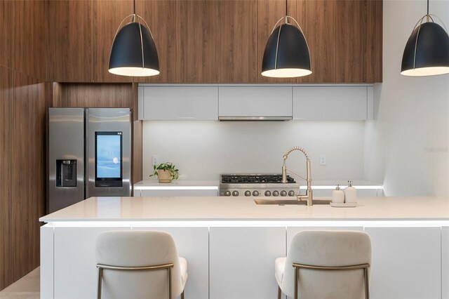 kitchen featuring hanging light fixtures, sink, white cabinets, and stainless steel refrigerator with ice dispenser