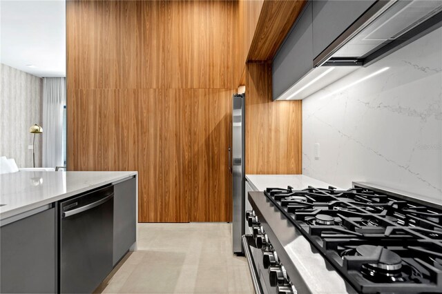 kitchen with gray cabinets, stainless steel appliances, and light stone countertops