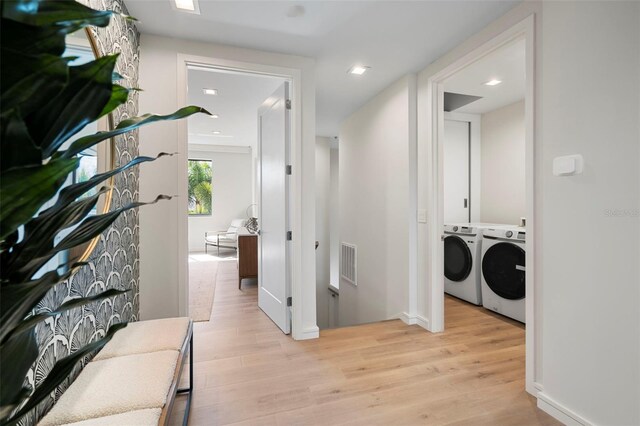 hall with washing machine and dryer and light wood-type flooring