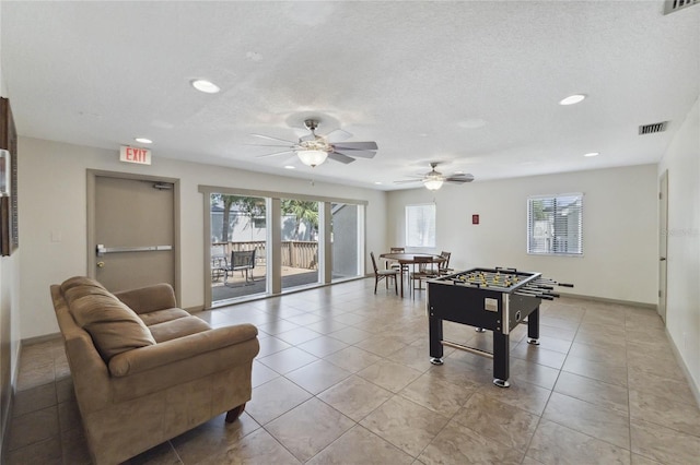 recreation room featuring ceiling fan, light tile patterned floors, and a textured ceiling