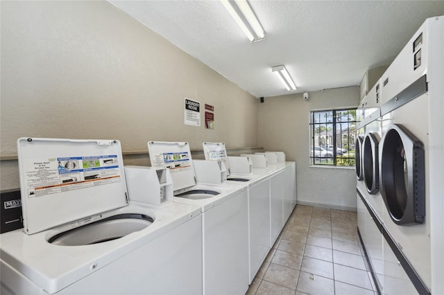 washroom with light tile patterned flooring, washing machine and clothes dryer, and a textured ceiling